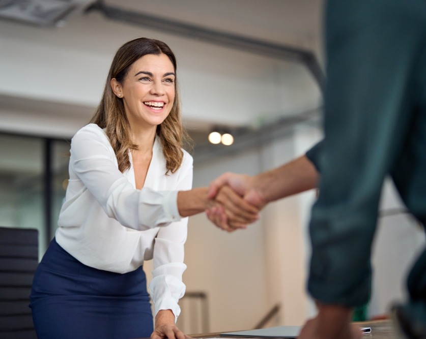 Woman Rising From Desk to Shake Hand_2353012835_edited